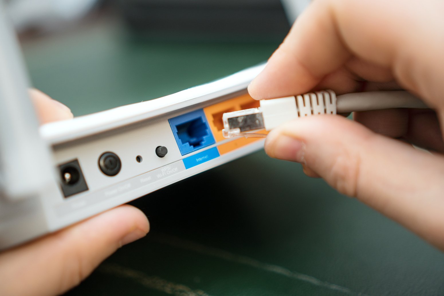 Man plugging internet cable into wifi router.